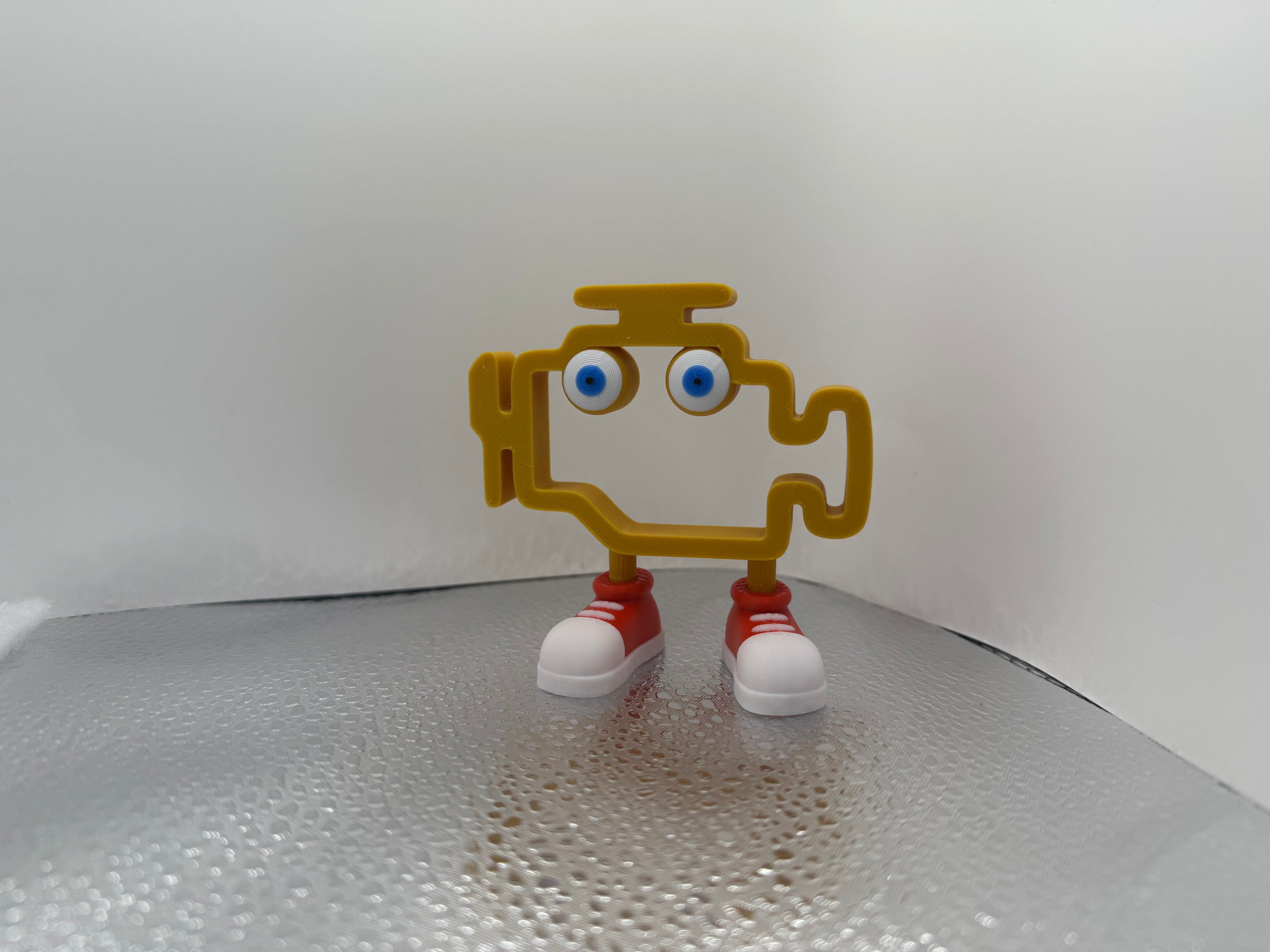 Small figurine with a yellow body, blue eyes, red shoes on a white background