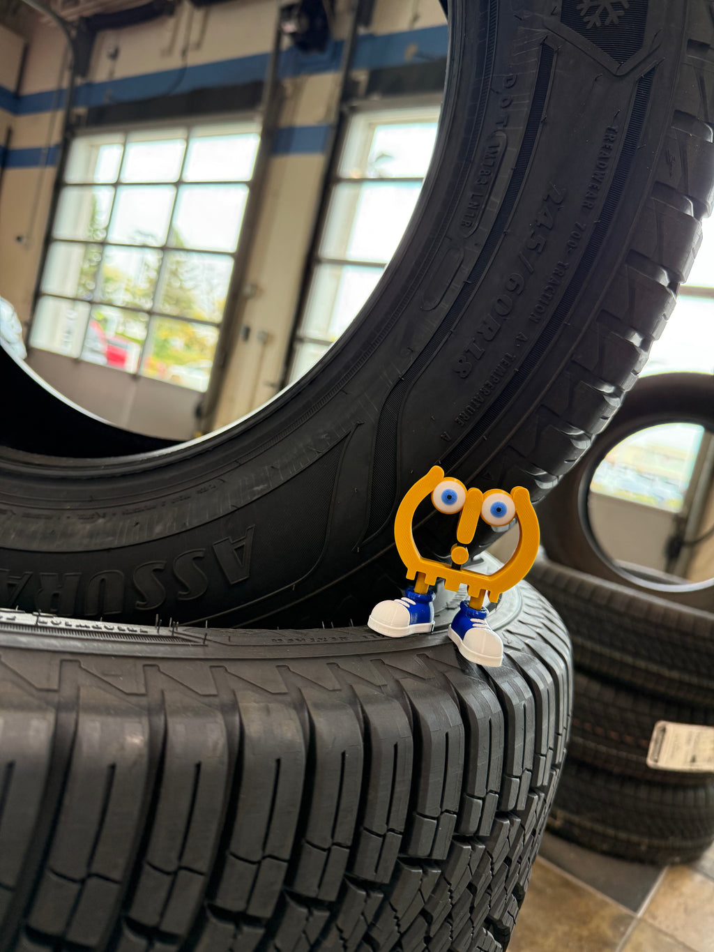 Tire with a small cartoon character on top in a garage setting