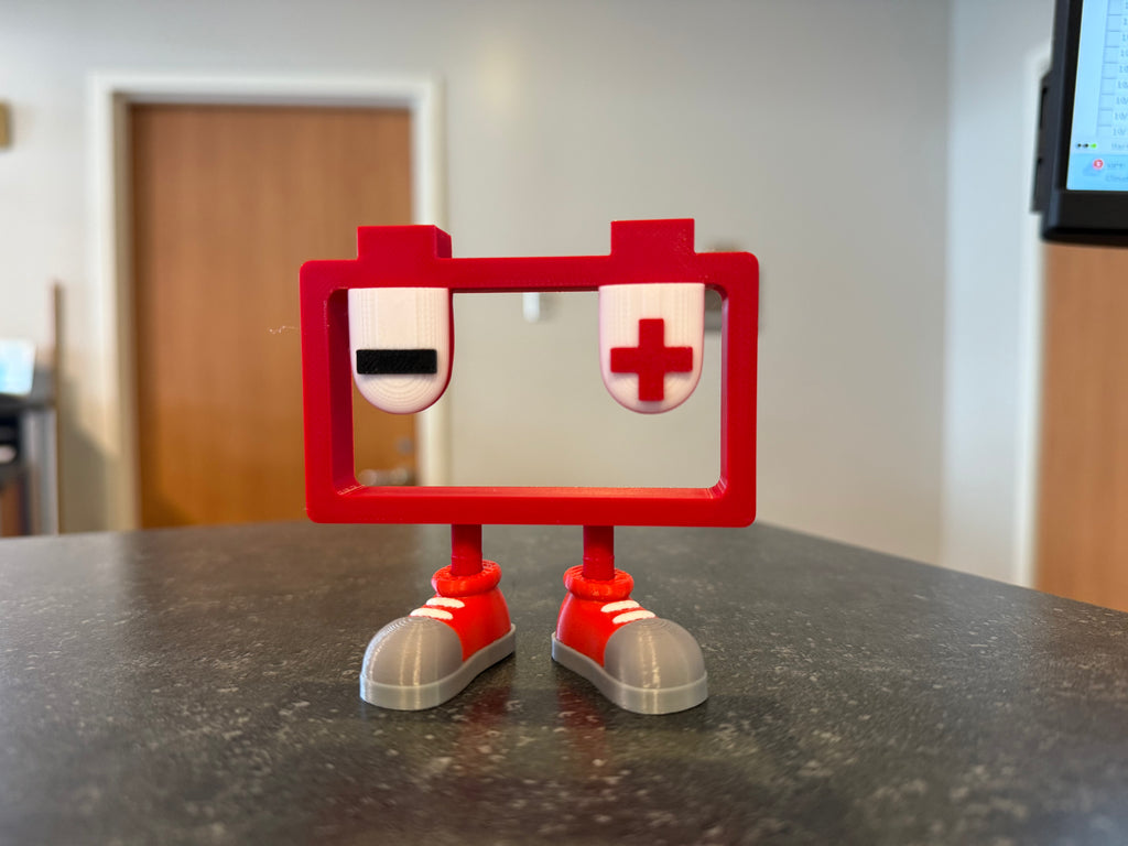 Red toy figure with a negative and positive sign on a gray surface
