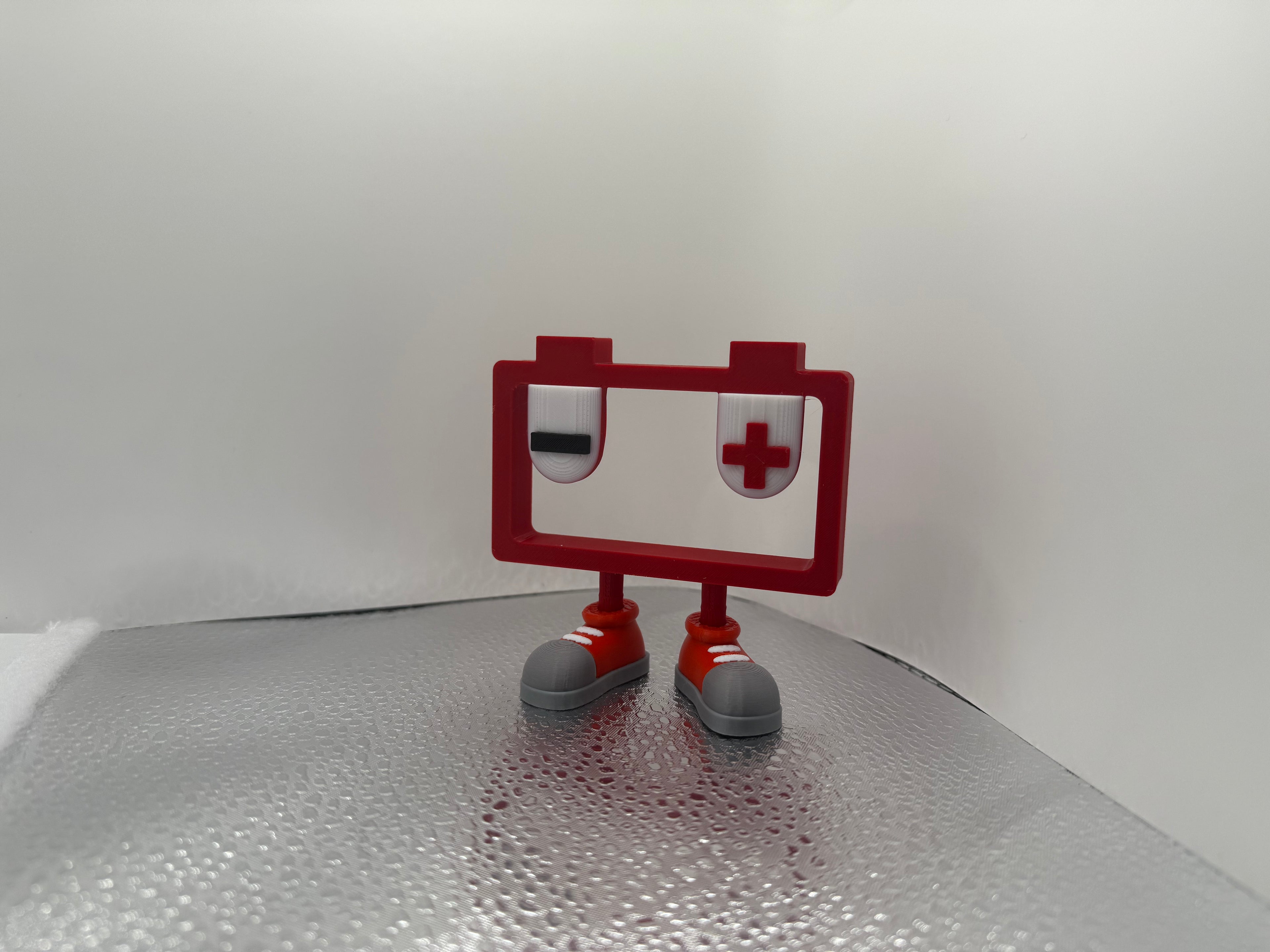 Small battery figurine with a red frame and gray shoes on a textured surface
