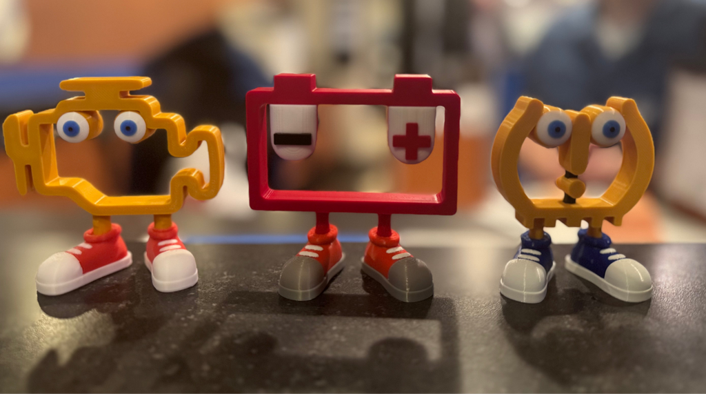 Three colorful toy figures on a table with a blurred indoor background